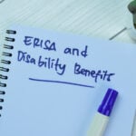 Concept of ERISA and Disability Benefits write on book isolated on Wooden Table.
