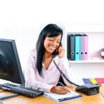 Smiling black businesswoman on phone at desk