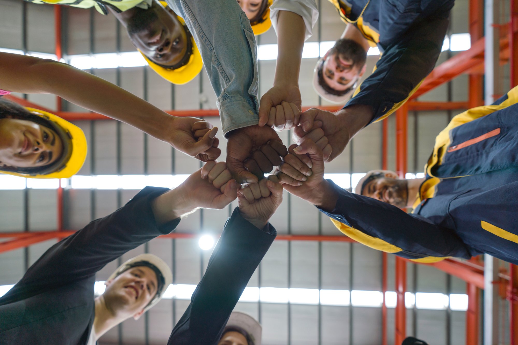 Group of male and female factory labor bump their fist together