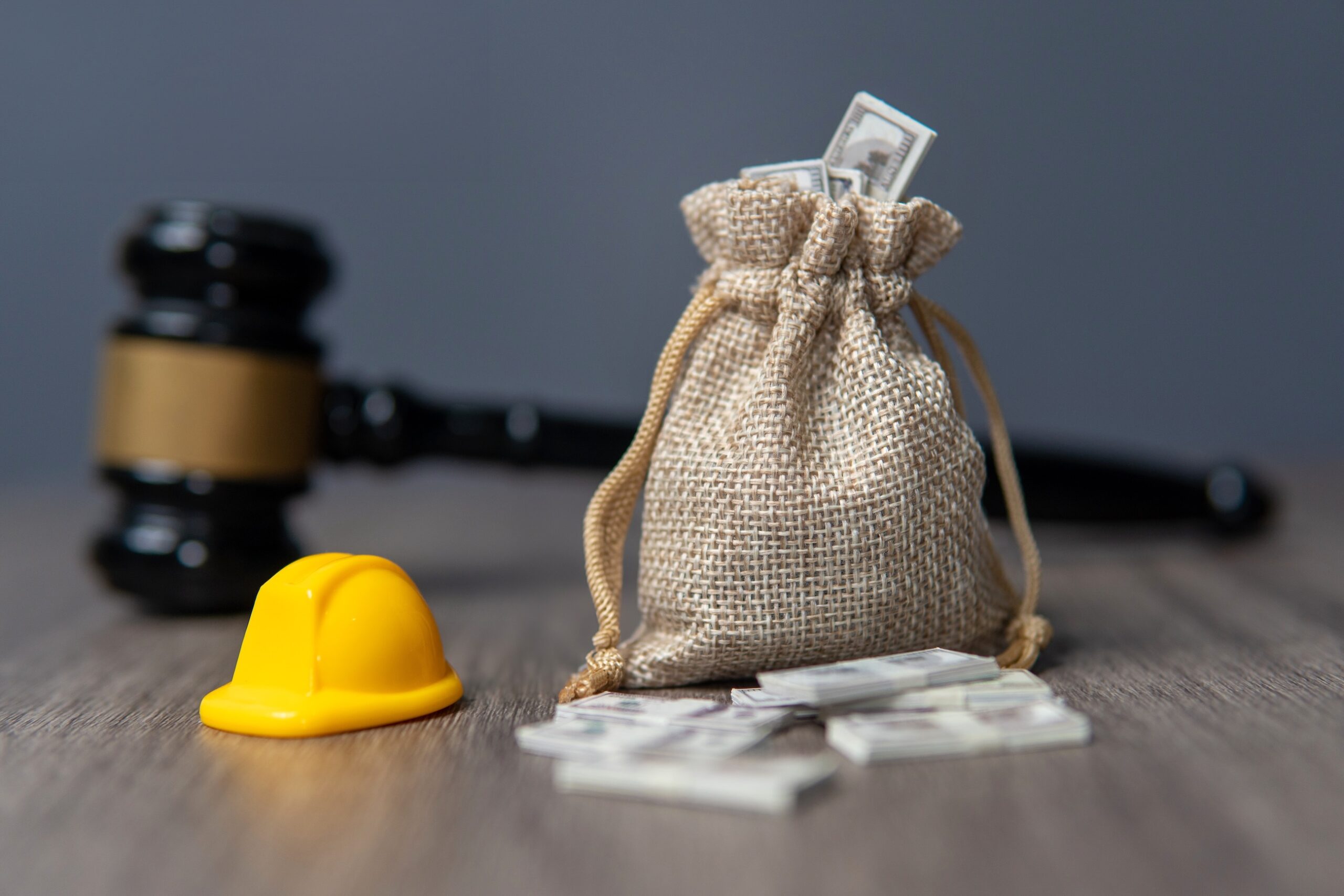Bag with cash next to a gavel and hardhat
