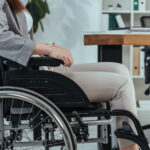 Cropped view of disabled employee in wheelchair at table