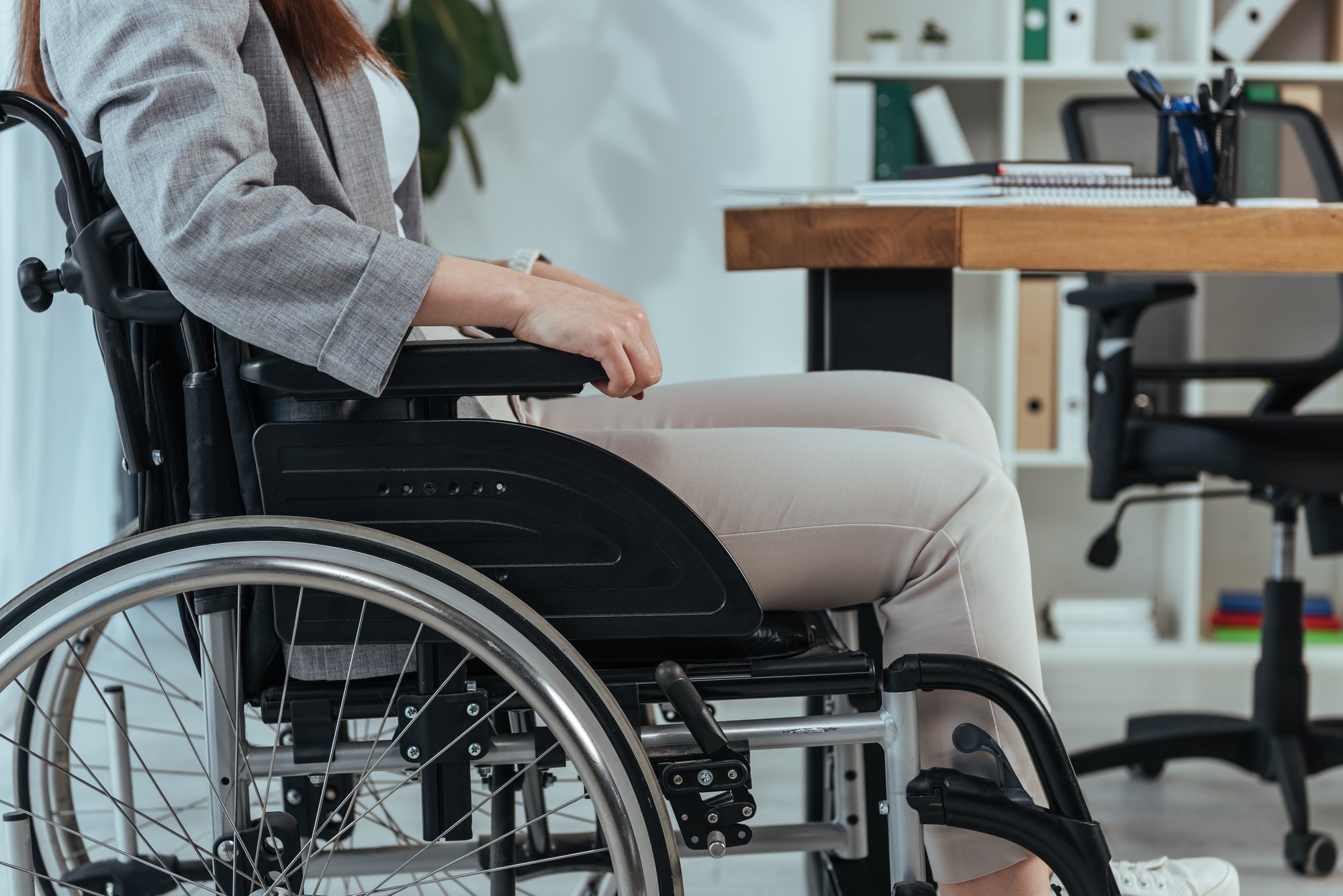 Cropped view of disabled employee in wheelchair at table