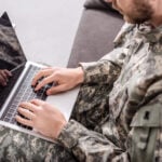 Partial view of army soldier using laptop on couch