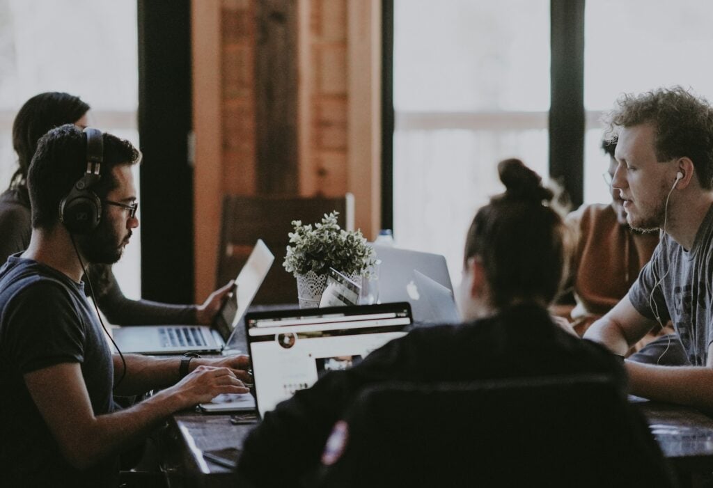 Employees working on laptops around a table