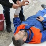 Injured Man lying on the Ground receiving a First Aid Treatment