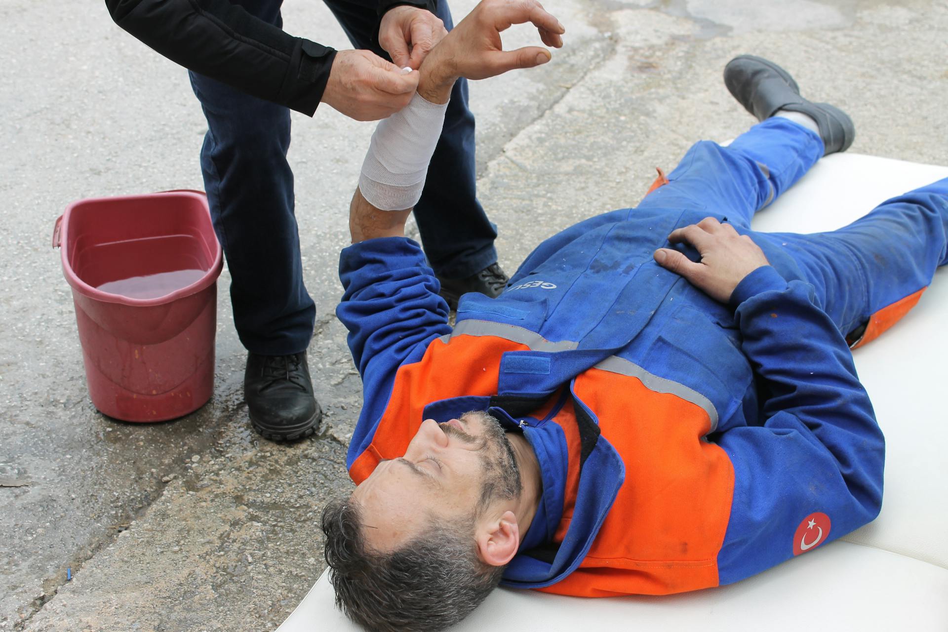 Injured Man lying on the Ground receiving a First Aid Treatment