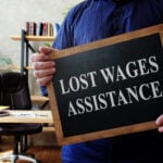 Man holds Lost Wages Assistance plate in the office