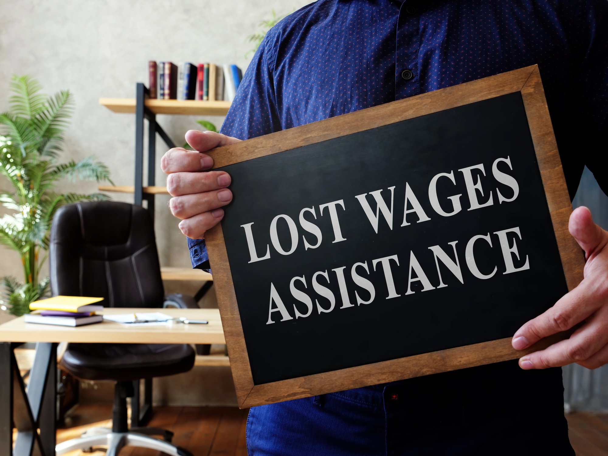 Man holds Lost Wages Assistance plate in the office