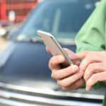 Man ordering taxi with smartphone on city street
