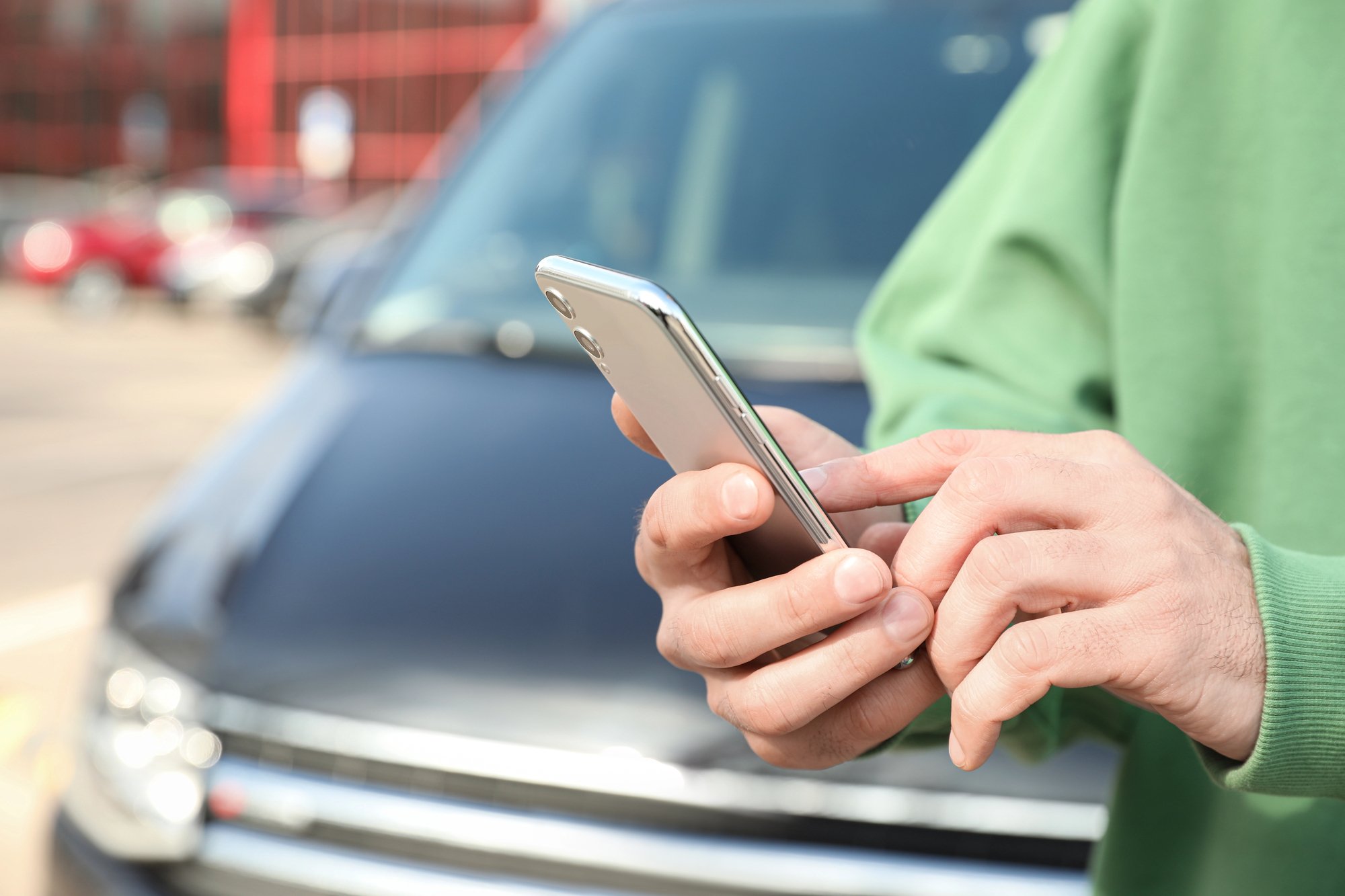 Man ordering taxi with smartphone on city street