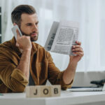 Selective focus of wooden cubes with lettering job and man talking on the phone