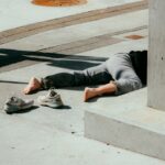 person in gray pants and gray shoes sitting on concrete bench