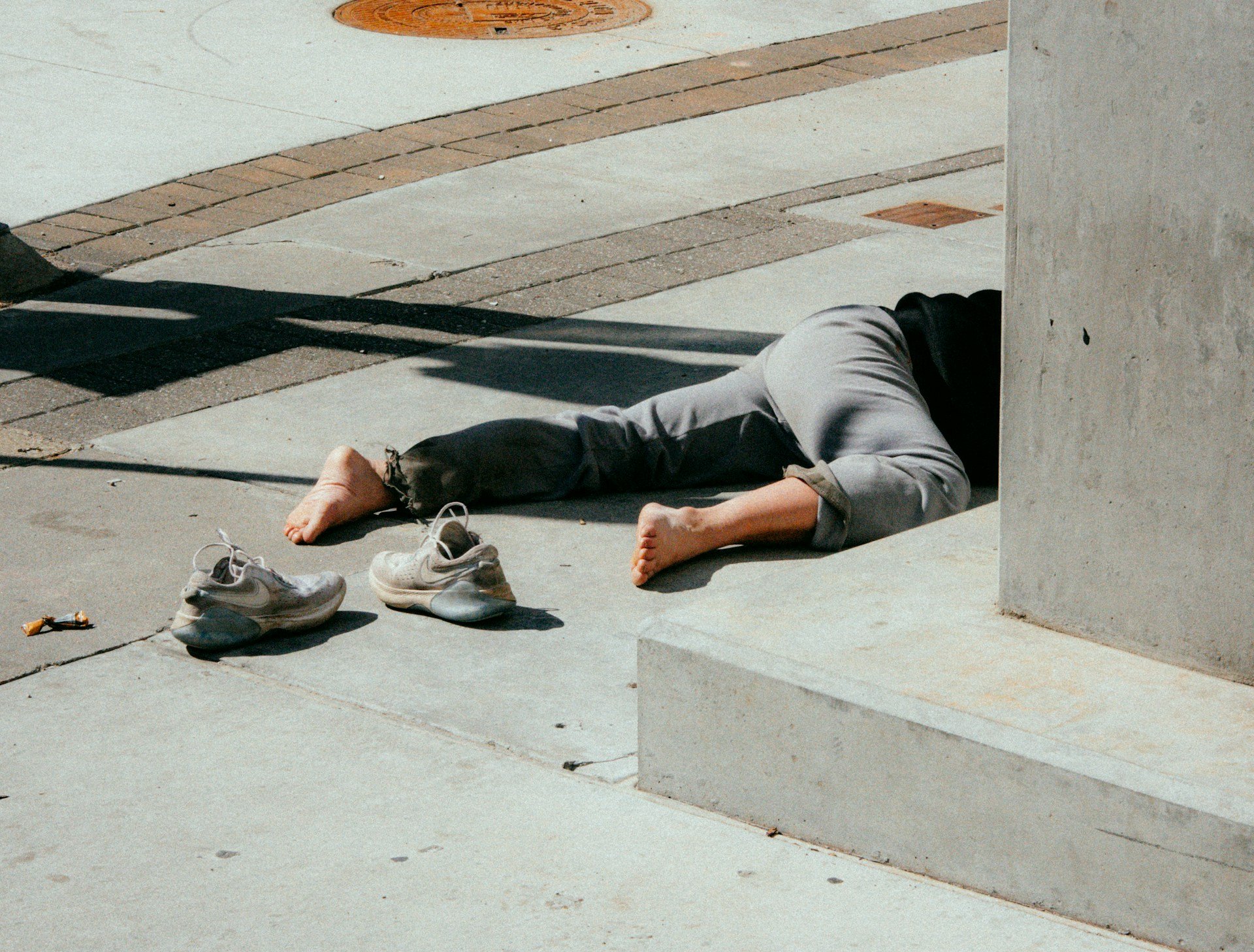 person in gray pants and gray shoes sitting on concrete bench