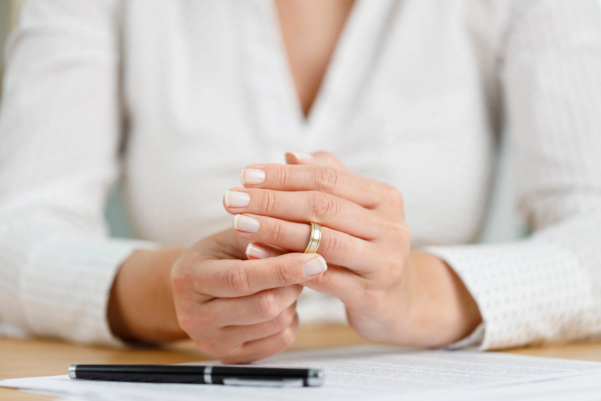 Hands of female who is about to taking off her wedding ring