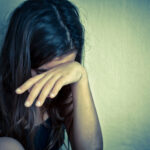 Lonely girl crying with a hand covering her face