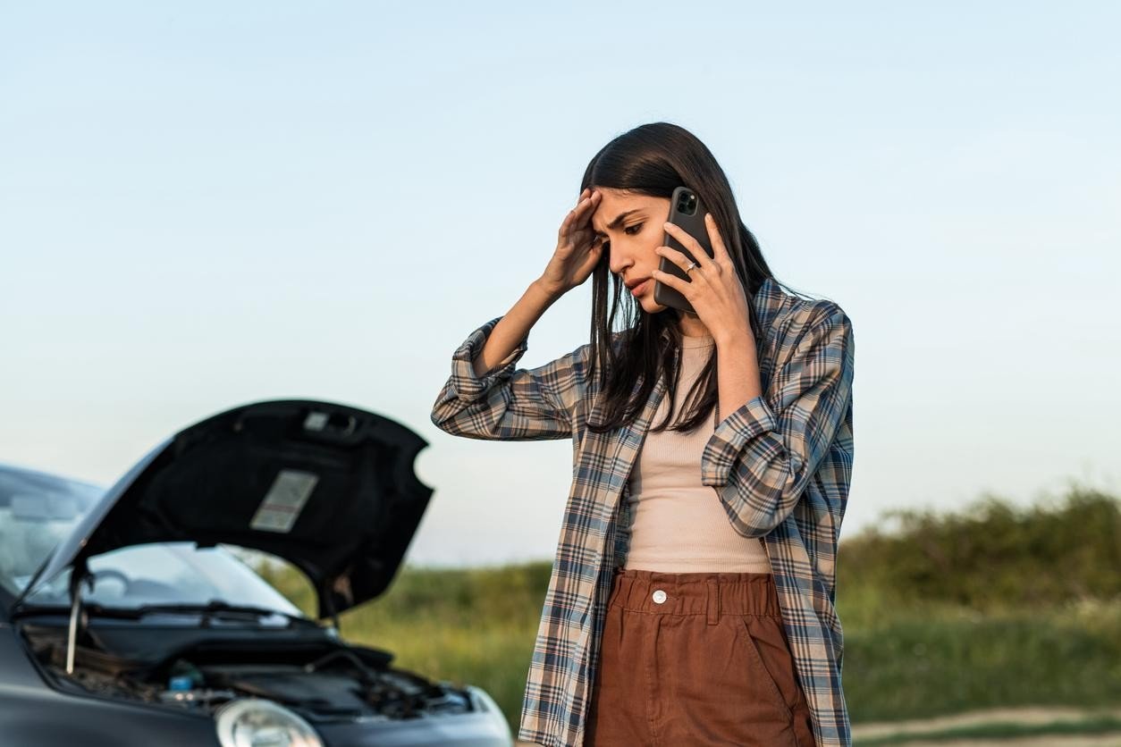 Stressed female standing by a broken car