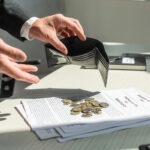 Cropped view of businessman holding empty wallet near coins