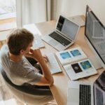 High-Angle Shot of a Boy Sitting on Grey Chair while Using His Laptop Computers
