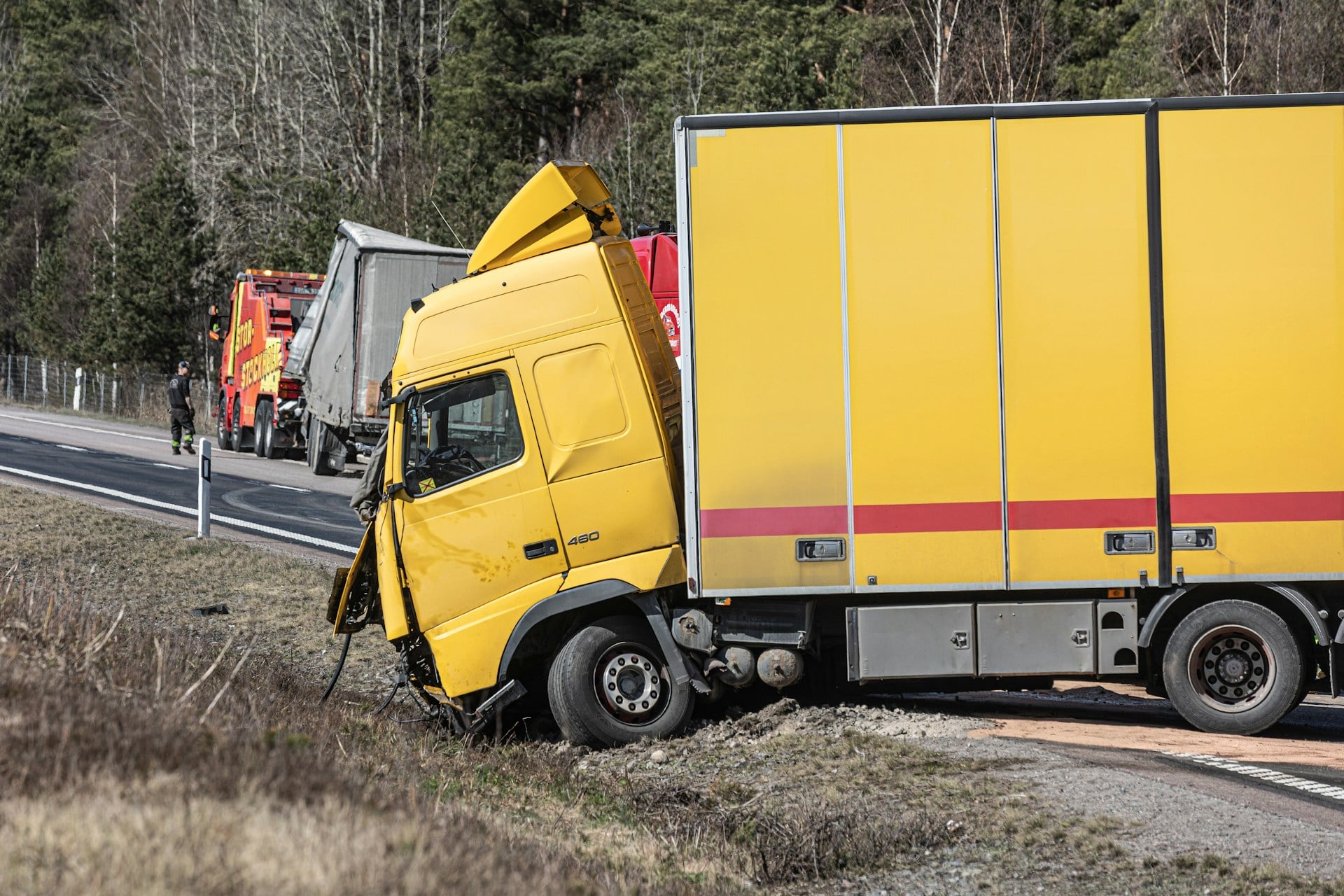 A yellow semi-truck is in a roadside accident.