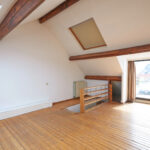 Interior attic windows and hardwood floor in empty room