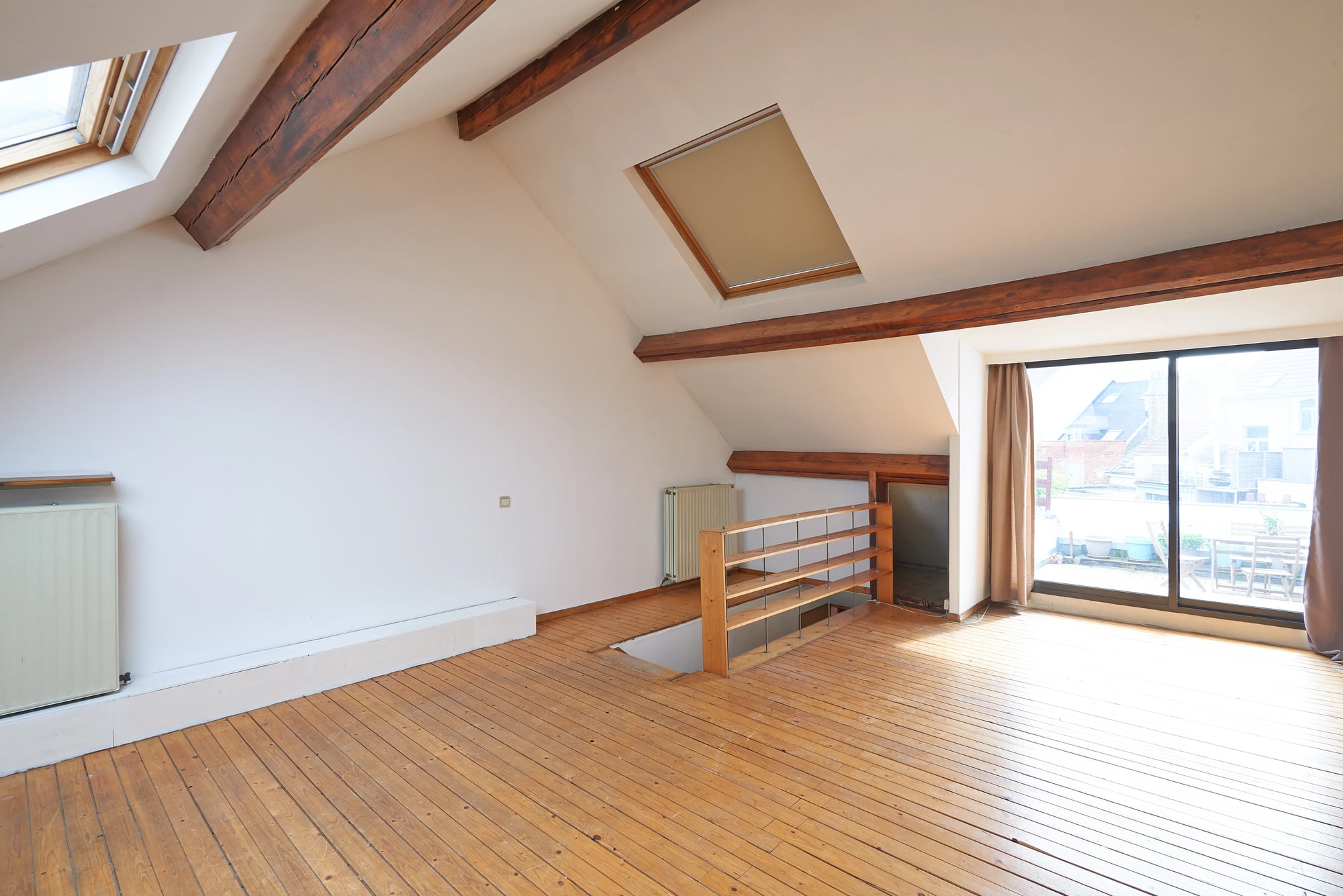 Interior attic windows and hardwood floor in empty room