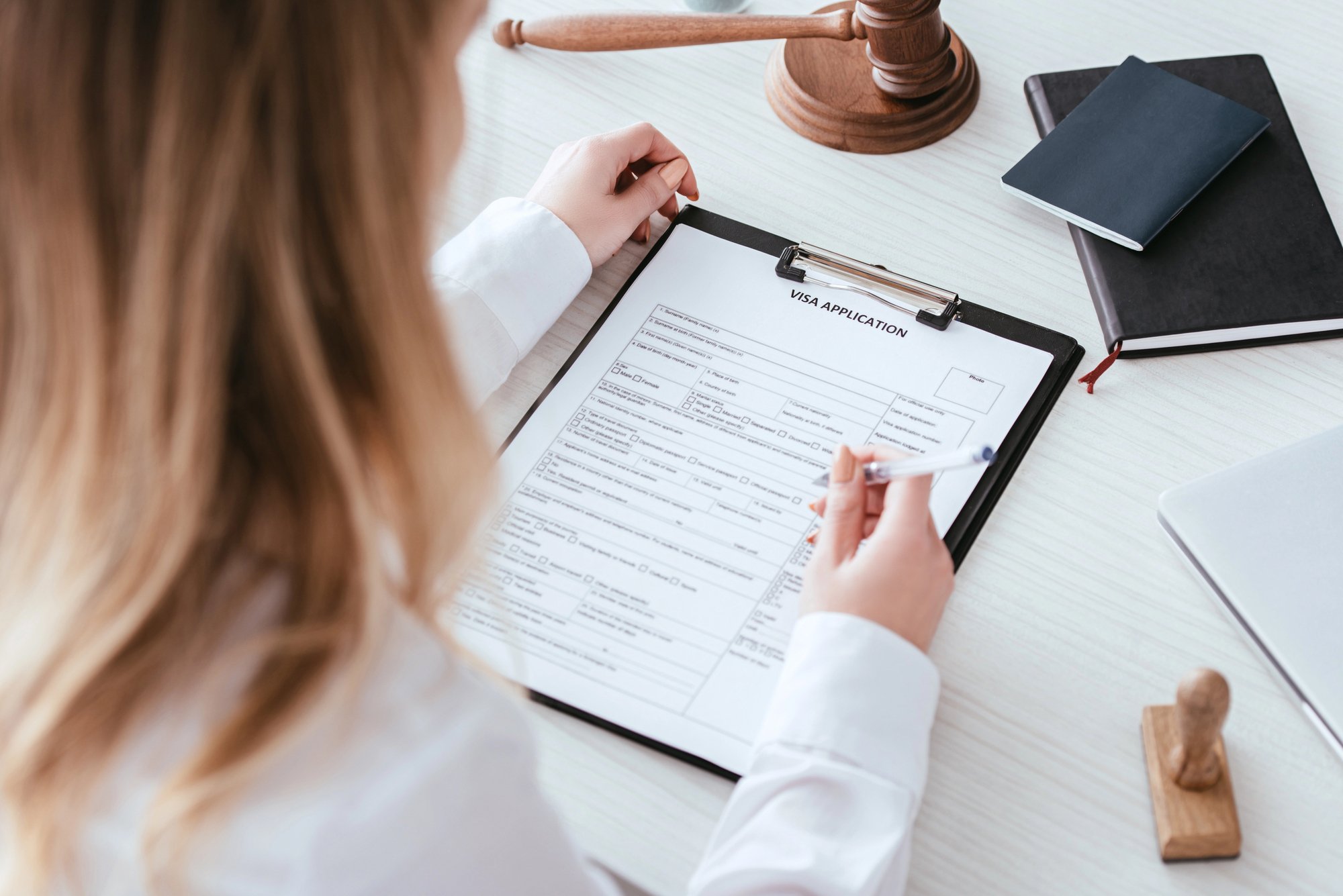 Selective focus of woman holding pen near document with visa