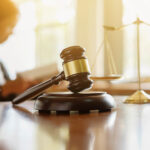 Gavel and scales of justice with attorney in the background