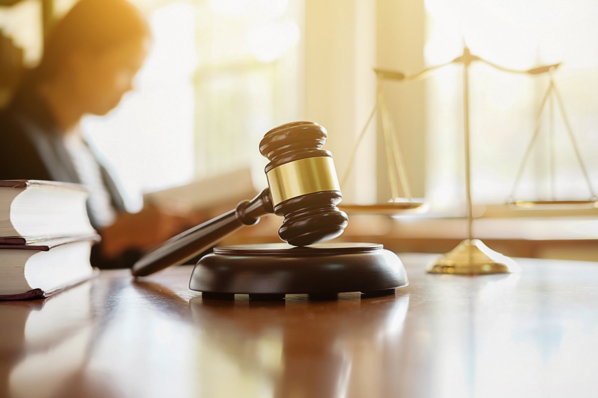 Gavel and scales of justice with attorney in the background