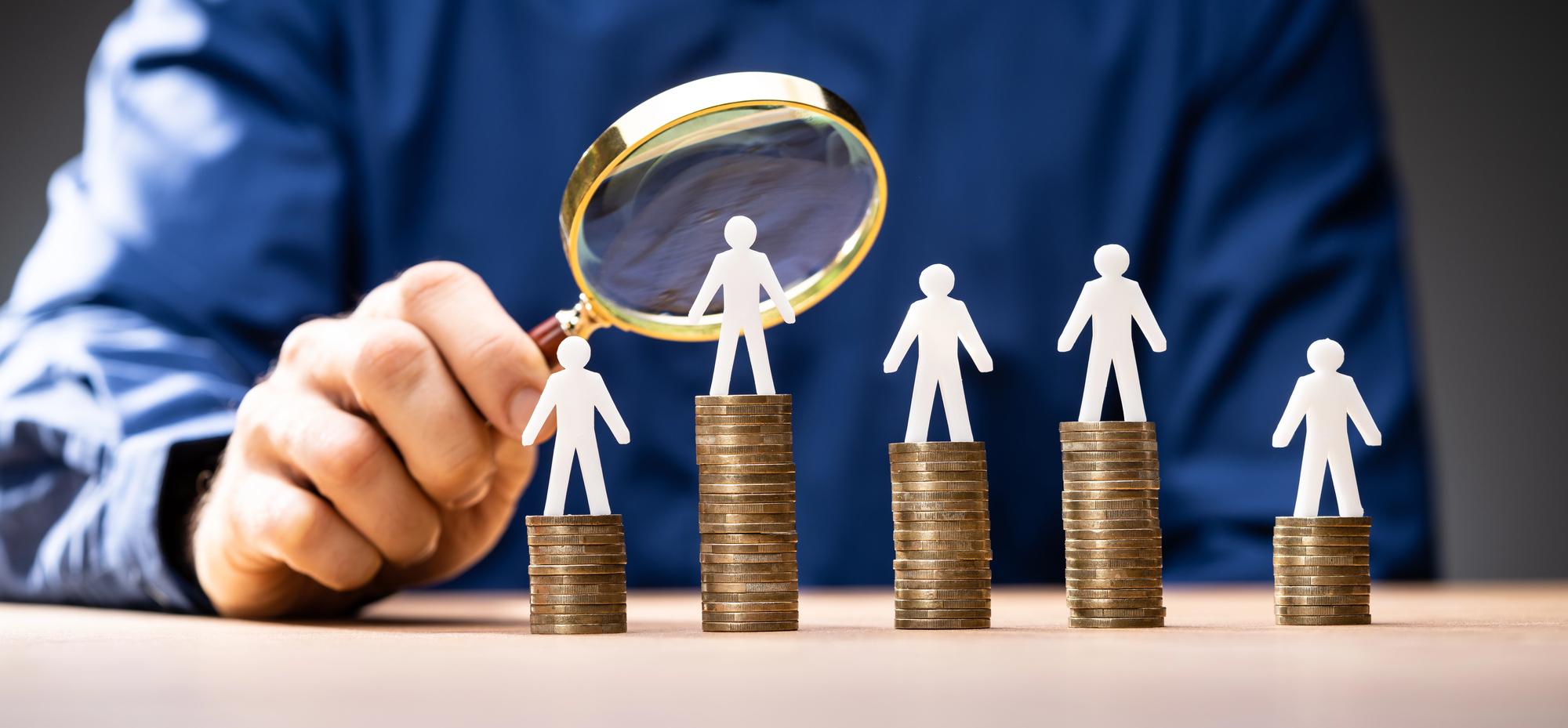 Man looking at stacks of coins with a magnifying glass