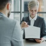 Woman in suit shows document to man