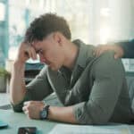 Man, sad and comfort in office, stress and thinking of unemployment, emotional and financial crisis. Employee, unhappy and person with depression for job loss and coworker with empathy for dismissal