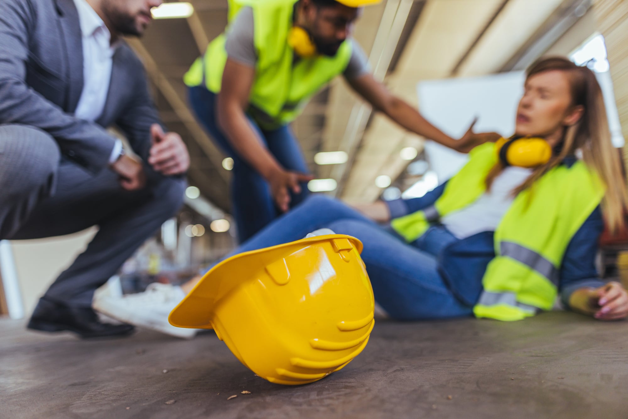 A workplace accident scene showing coworkers aiding a fallen worker