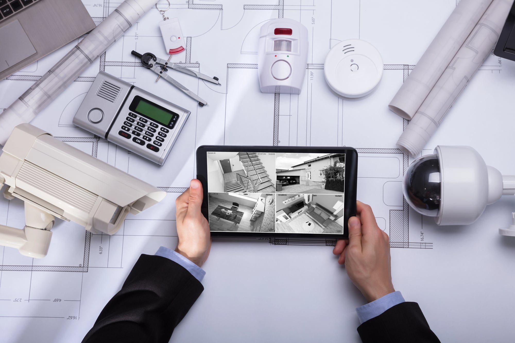 Person watching footage on digital tablet with security equipment on a table