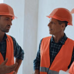 Builders in safety helmets talking on construction site
