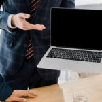 Male employee holding laptop with blank screen