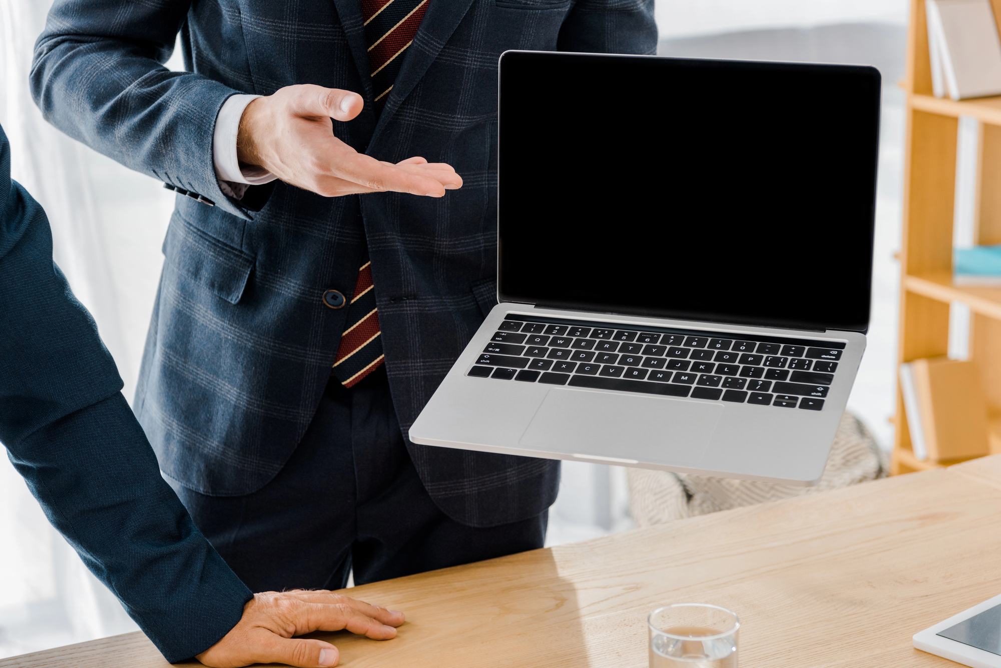Male employee holding laptop with blank screen