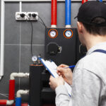 Technician servicing holding clipboard and inspecting heating