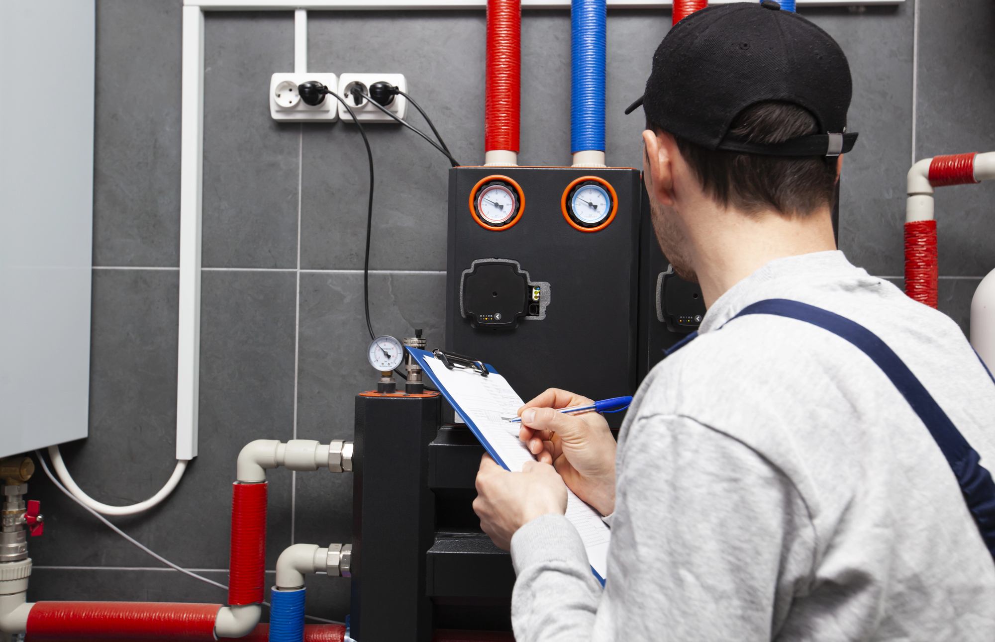 Technician servicing holding clipboard and inspecting heating