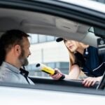 A police officer conducts a breathalyzer test on a male driver during a road safety check