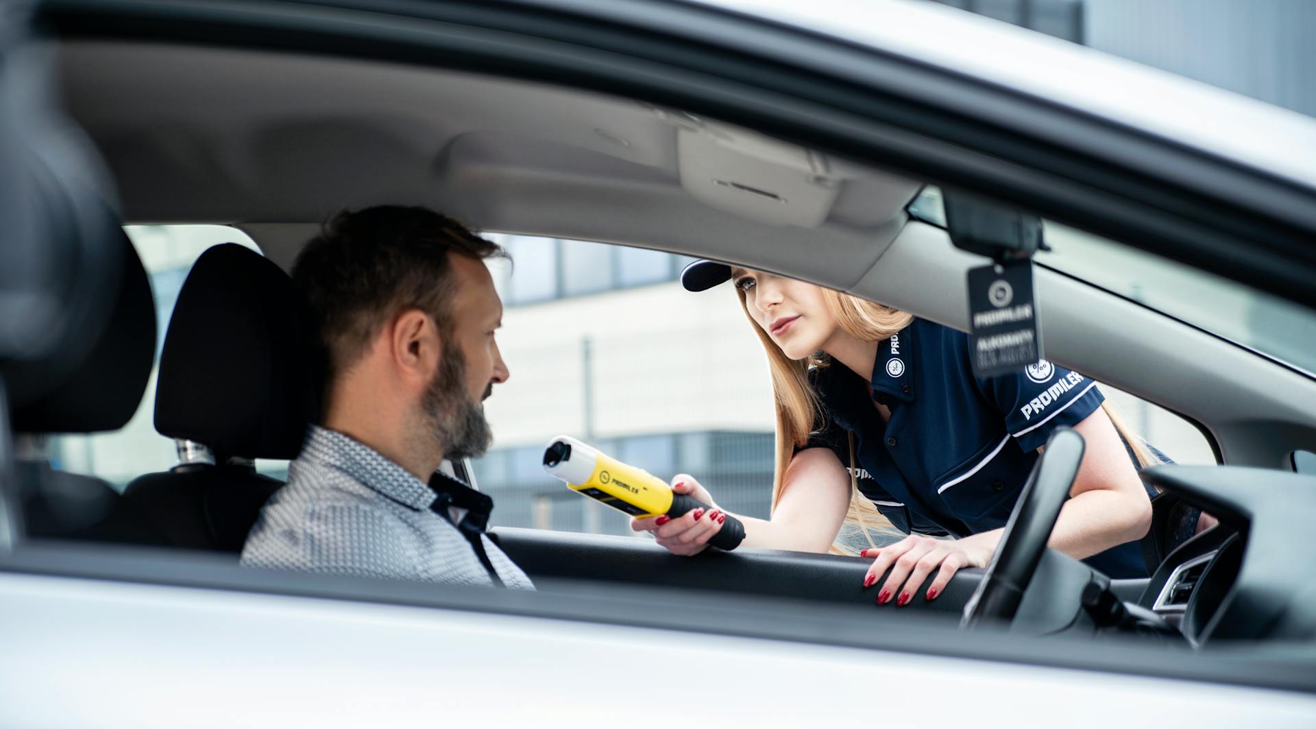 A police officer conducts a breathalyzer test on a male driver during a road safety check