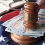 Close-up of a judge's gavel resting on US dollar bills and an American flag