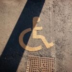 Close-up of a yellow wheelchair symbol painted on asphalt