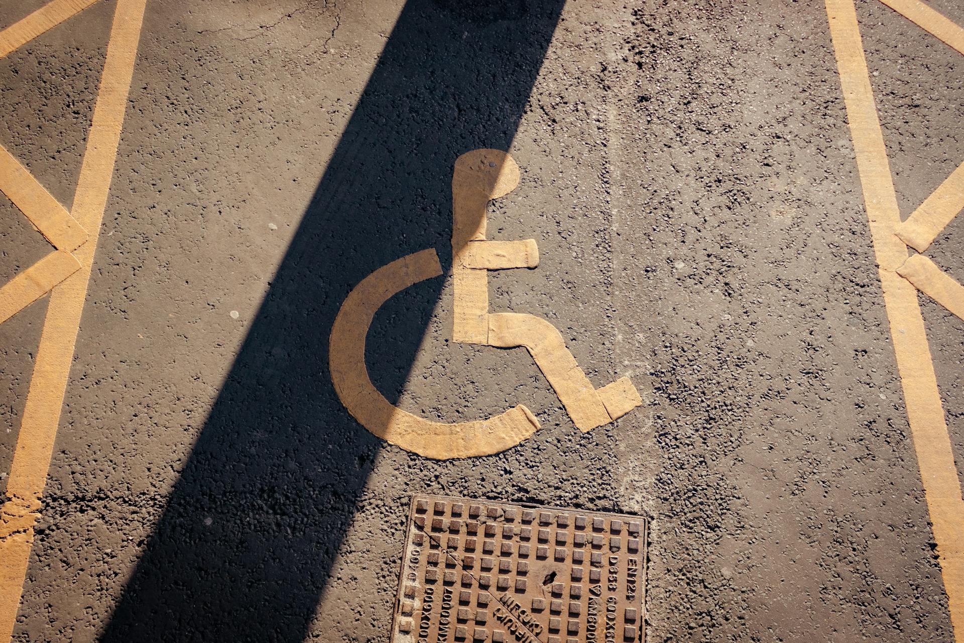 Close-up of a yellow wheelchair symbol painted on asphalt