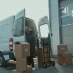 Courier loading cardboard boxes into a delivery