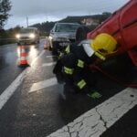 Firefighter attending to an overturned car on a rainy road