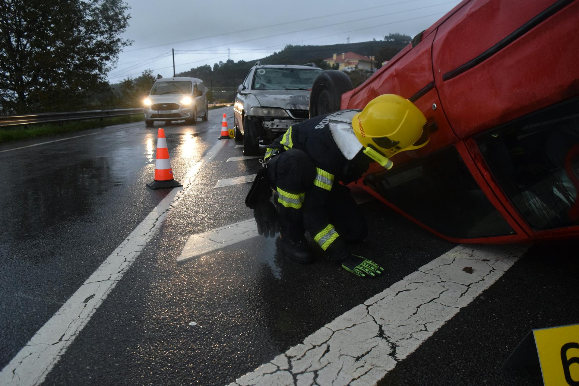 Firefighter attending to an overturned car on a rainy road