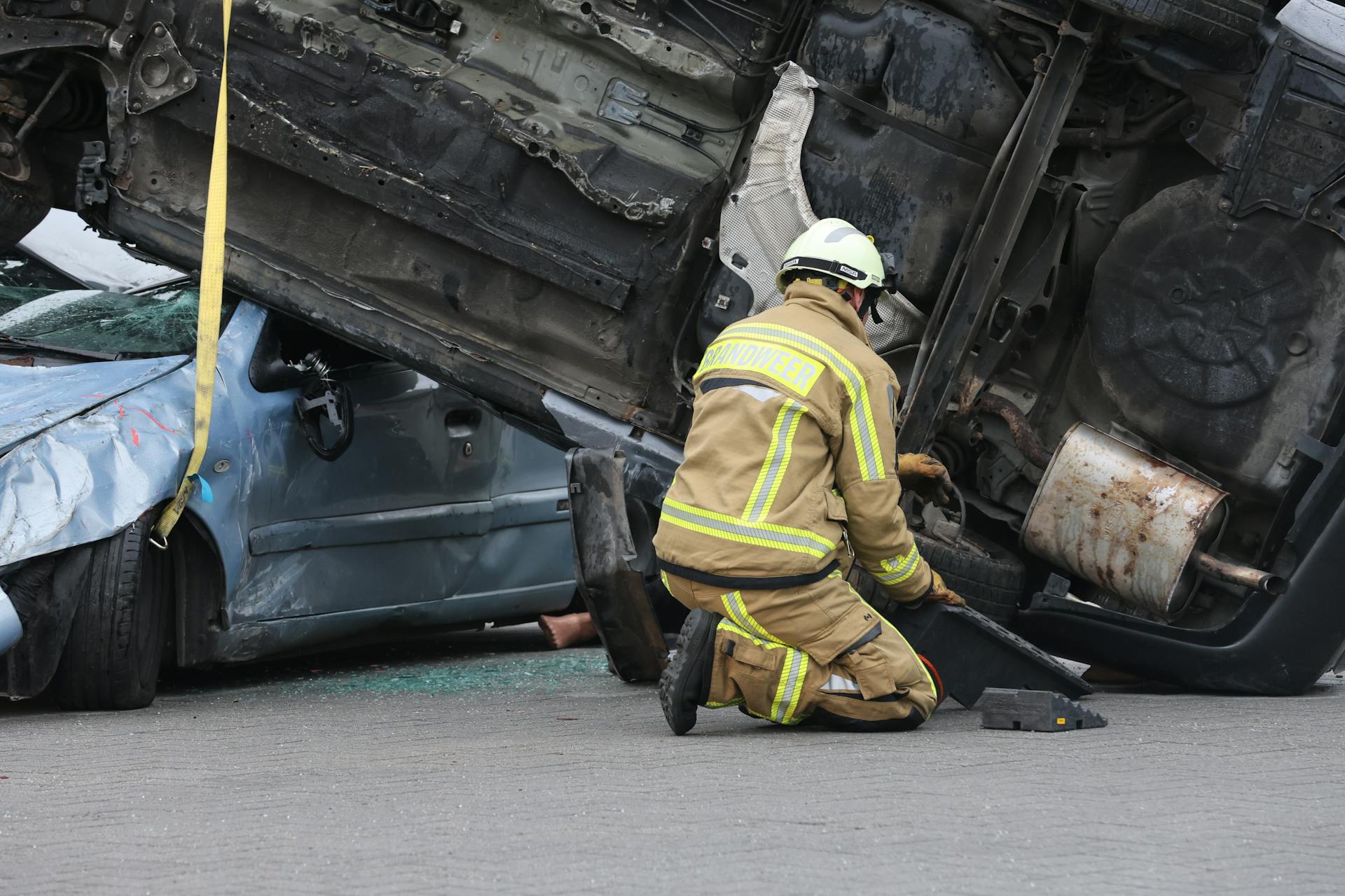 Firefighter in gear assisting at an overturned car crash scene