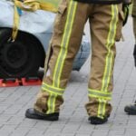 Firefighters inspecting a car accident wearing protective gear