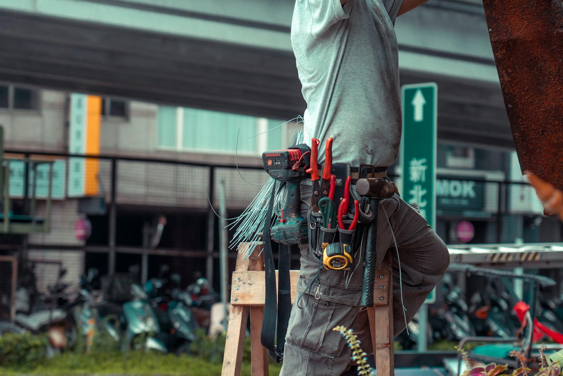 Handyman standing on a ladder with tool belt