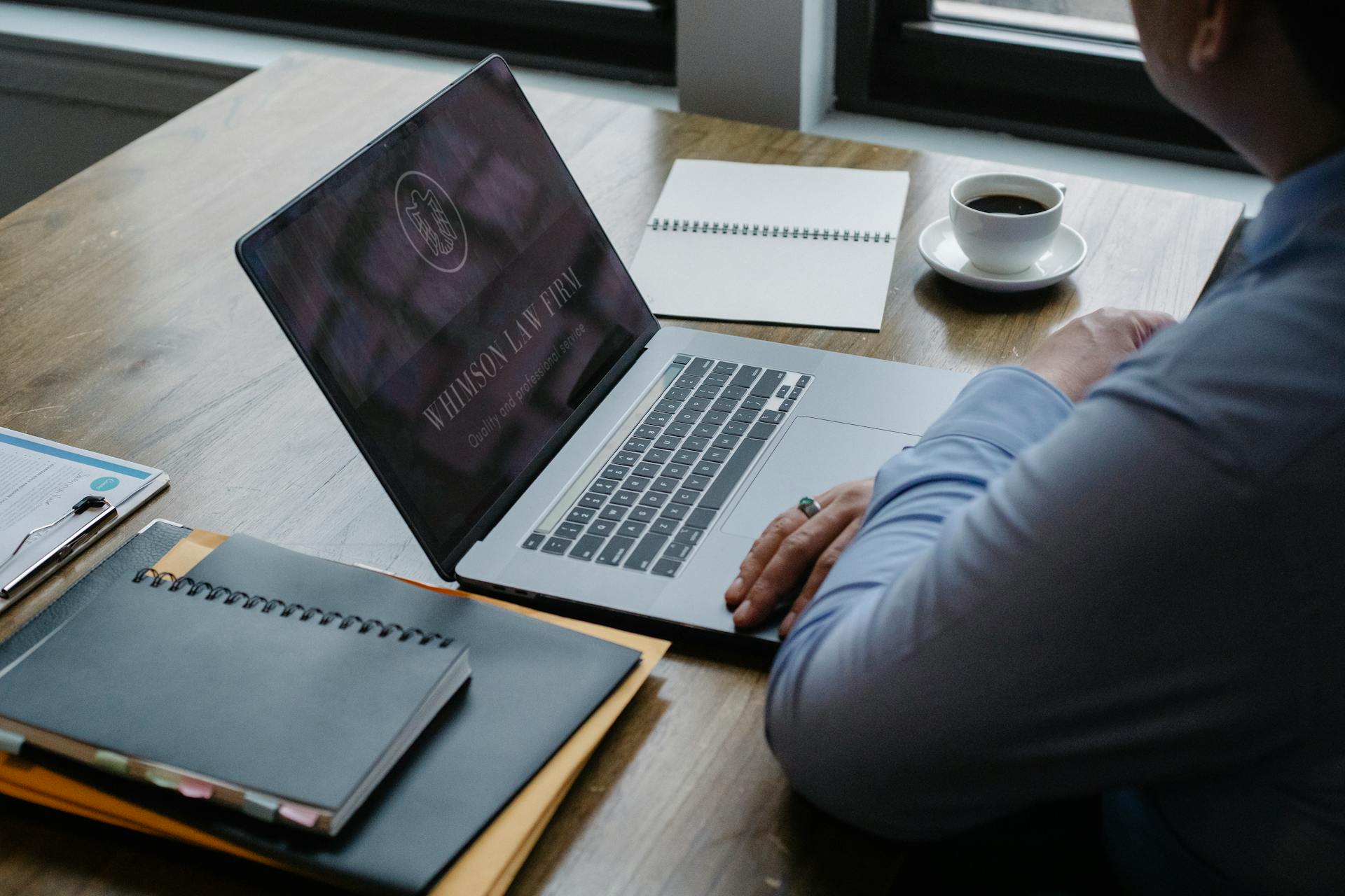 Lawyer using laptop at modern workplace with coffee and documents